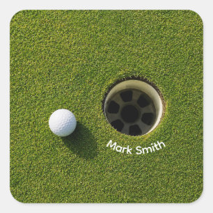 Golfball neben Loch auf grünem Rasen Golfplatz  Quadratischer Aufkleber