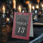 Gothic Black Raven & Black Arch Tischaufsteller<br><div class="desc">Mit unserem Vintag gotischen Zelt für Hochzeitszelt bringen Sie Ihre Gäste in eine Welt der dunklen und bezaubernden Eleganz. Der tiefrote Hintergrund im alten Bordeaux-Stil Set die Bühne für einen auffallenden Kontrast, da fett weißer Text aus den komplizierten schwarzen Textfeldern entsteht. Am Höhepunkt dieses Designs nimmt ein dreidimensionaler gotischer Rahmen,...</div>
