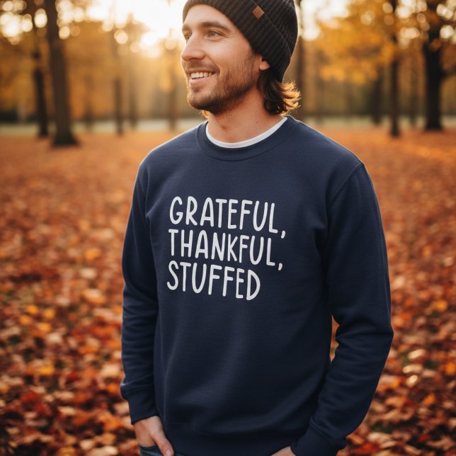 Grateful Thankful Stuffed • Funny Thanksgiving Sweatshirt (Man wearing navy sweater with text “Grateful, Thankful, Stuffed” in autumn park)