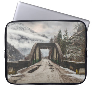 GRAUE BETONBOGENBRÜCKE NEBEN BLATTLOSEM BAUM IN DE LAPTOPSCHUTZHÜLLE
