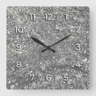 Grauer Granit mit weißen Elementen vermischt. Quadratische Wanduhr