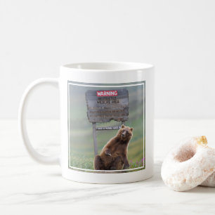 Grizzlybär spielt mit Schild Kaffeetasse
