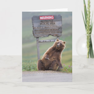 Grizzlybär spielt mit Schild Karte