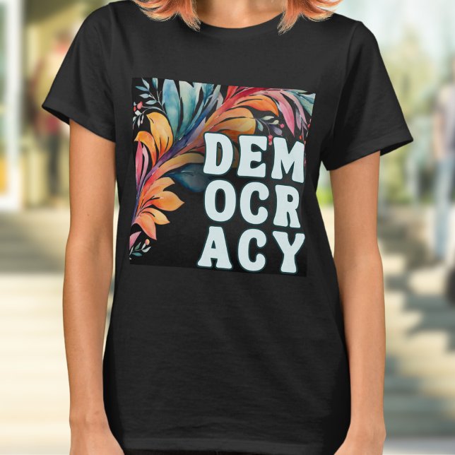 Groovy Retro farbenfrohe Erklärung Demokratie T-Shirt (A t-shirt with 'Democracy' in capital letters in a retro groovy style, on a colorful leafy backdrop)