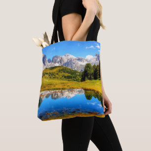 Grüne Landschaft mit Teich und schneebedeckten Ber Tasche
