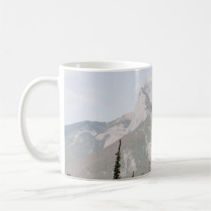 GRÜNE PINENBÄUME IN DER NÄHE DES BERGS UNTER WEISS KAFFEETASSE