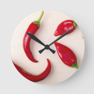 Heiße rote Chili-Paprikaschoten auf einem hellen Runde Wanduhr