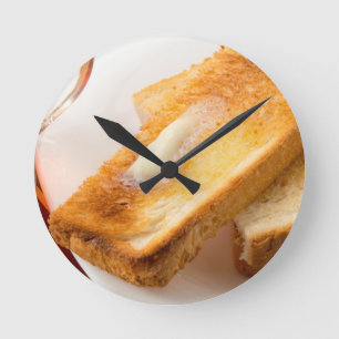 Heißer Toast mit Butter auf einer weißen Runde Wanduhr