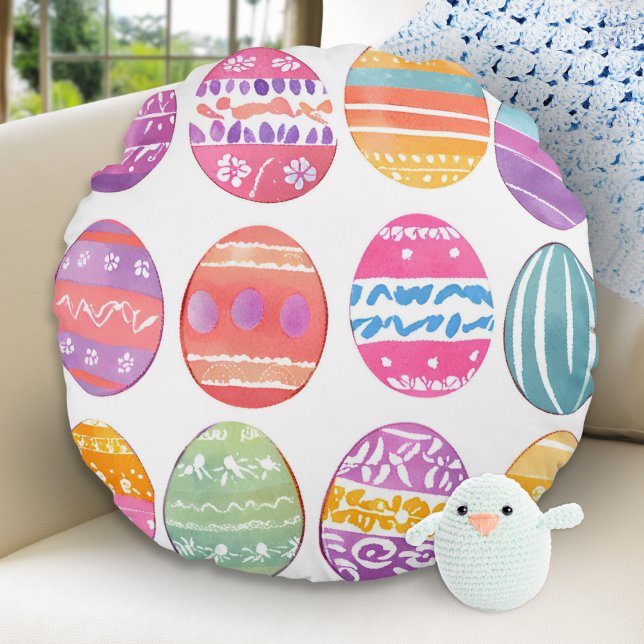 Helles Gemustertes, buntes Ostereier Kissen (A round throw pillow with a bright, colorful pattern of Easter eggs on a white background)
