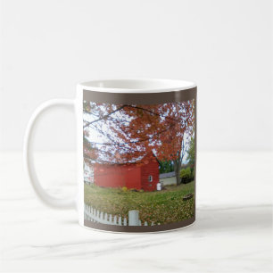 Herbstblätter und eine süße rote Scheune auf ei Kaffeetasse