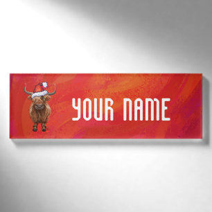 Hochlandkuh in Weihnachtsmannmütze auf Rot Namenschild