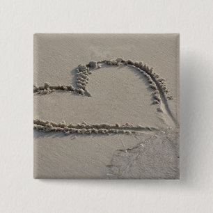 Hohe Winkelsicht einer Herzform auf dem Strand Button
