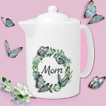 Hübscher Kranz mit Schmetterlingsmüttern Teekanne<br><div class="desc">Eleganter weißer Teekanne mit hübscher Pflanze-Blätterkranz,  3D-Schmetterlinge und grüner Text-Lesekatze mit Mama. Liebliche Geschenkidee für Mutter am Muttertag. Den China-Becher mit passenden Knochen liefern.</div>