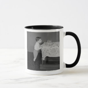 Junge bläst Kerzen aus Tasse