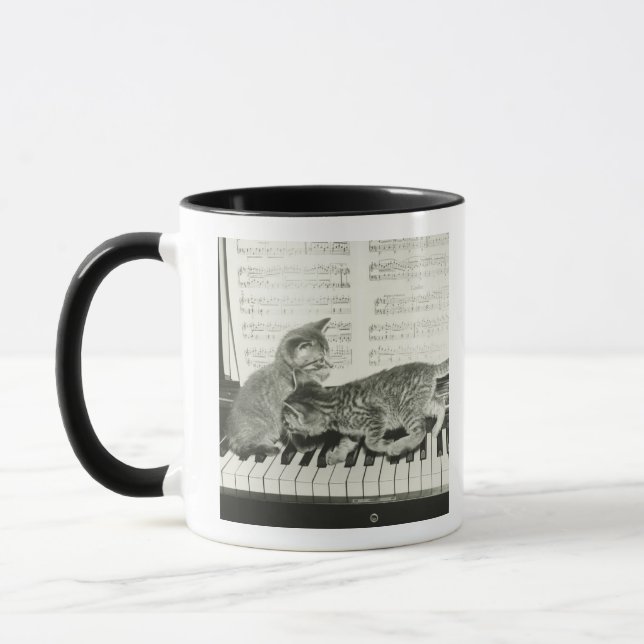 Kätzchen zwei, das auf Klaviertastatur spielt, Tasse (Links)