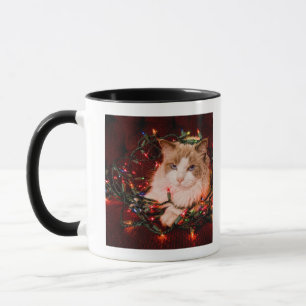 Katze, die auf einem Ball der Weihnachtslichter Tasse