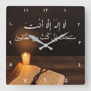 Kerze und Quran mit Perle im dunklen Raum Quadratische Wanduhr
