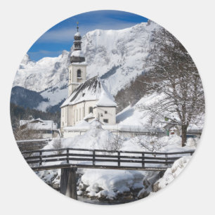 Kirche im Schnee mit den Alpen Runder Aufkleber