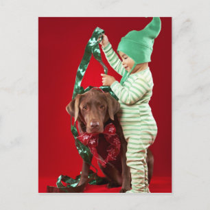 Kleiner Junge, der einen Hund verziert Feiertagspostkarte