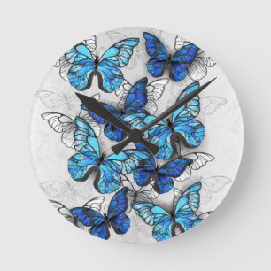 Komposition aus weißen und blauen Schmetterlingen Runde Wanduhr
