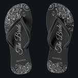 Lacy Silver on Black Elegante The Bride Wedding Flip Flops<br><div class="desc">Tanzen Sie die Nacht mit diesen schönen Hochzeitsflip-Flops. Sie sind für die Braut konzipiert und zeichnen sich durch ein schlichtes und elegantes Design aus, das auf einem klassischen schwarzen Hintergrund mit grauen Schriftzeichen und extravaganten, silbergrauen Zierbögen und Wirbel versehen ist. Eine schöne Art, extravagant und angemessen bleibe, während Sie Ihren...</div>