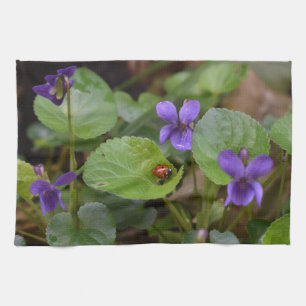Ladybug über süße Violettsorten-Blume Geschirrtuch