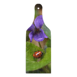 Ladybug über süße Violettsorten-Blume Schneidebrett