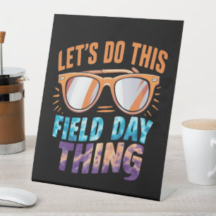 Lasst uns diese Field Day Sache Sonnenbrille Lehre Sockelschild