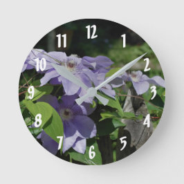 Lila Clematitis-Blume auf Zaun Runde Wanduhr