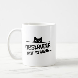 Lustige schwarze hinterlistige Katze beobachtet, s Kaffeetasse