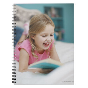 Mädchen, das in Bettlesebuch legt Notizblock