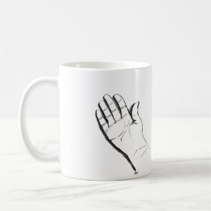 main noire et blanche sur une tasse à café