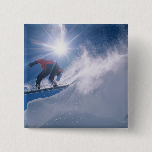 Man springt von einer großen Ecke auf einem Snowbo Button (Vorderseite)