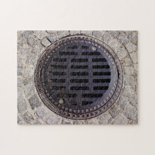 Manhole-Abdeckung und Coblestone-Straße