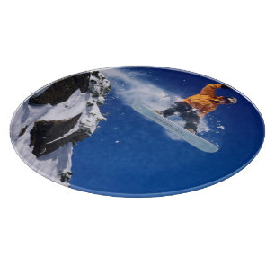 Mann auf einem Snowboard, der von einem Gesims spr Schneidebrett