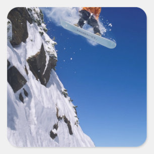 Mann auf einem Snowboard springt von einem Kornfle Quadratischer Aufkleber