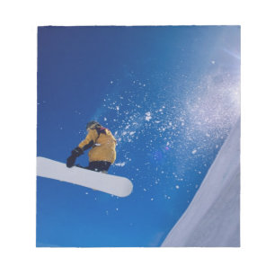 Mann fliegt durch die Luft auf einem Snowboard mit Notizblock