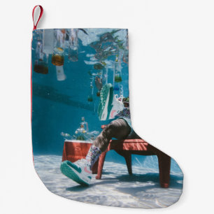 Mann sitzt auf Stuhl unter Wasser mit schwimmendem Kleiner Weihnachtsstrumpf