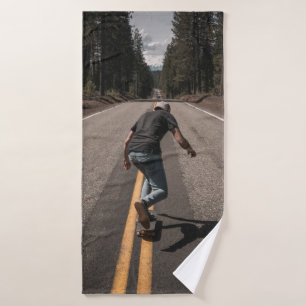 Mann spielt morgens Skateboard auf der Straße Badehandtuch