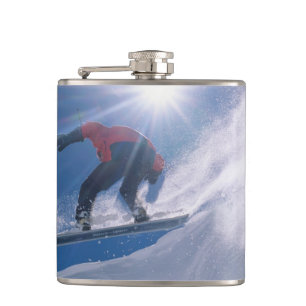 Mann springt auf einem Snowboard von einer großen Flachmann