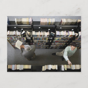 Männer in der Bibliothek, die nach Büchern sucht Postkarte