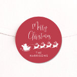 Merry Christmas Santa Reindeer Sleigh Red Runder Aufkleber<br><div class="desc">Vergnügen saisonale Rot-Weiß-Aufkleber für Ihre Weihnachtskarten und Geschenke mit einer Silhouette von Rentieren,  die den Schlitten des Weihnachtsmanns durch Luft fliegen,  "Frohe Weihnachten" in einem modernen Drehbuch und Ihren Namen in einfacher Typografie.</div>