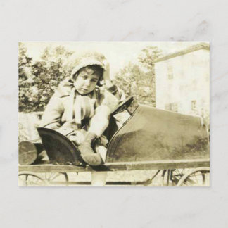 Mignonne fille dans une voiture à pédales carte po