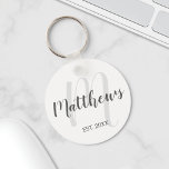 Modern Script Personalisiert Monogram und Familien Schlüsselanhänger<br><div class="desc">Personalisiertes Monogramm und Familiennamensgeschenk mit Familiennamen in grauem,  modernem Script Schriftart Stil und Monogramm in hellgrauem,  modernem Script Schriftart Stil als Hintergrund mit einem Jahr in Grausans Serif Schriftart Stil auf weißem Hintergrund. Perfekt als Geschenk für Neuvermählte,  Familiengeschenk,  Familienspass und Wiedersehen für alle besondere Anlässe.</div>