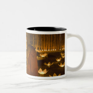 Mönche zünden Khom Loy-Kerzen und Laternen für Zweifarbige Tasse