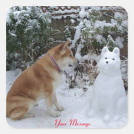niedliche akita sitzt mit Schneemann im Schneehund Quadratischer Aufkleber