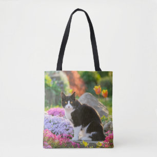 Niedliche Schwarz-weiße Katze in einem blühenden Tasche