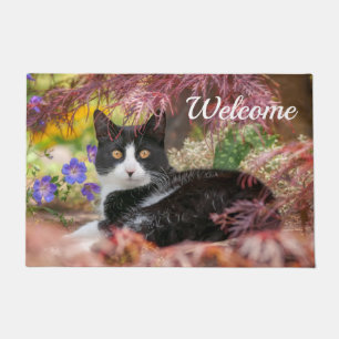 Niedliche schwarz-weiße Katze unter einem Ahornba Fußmatte