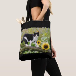 Niedliche Tuxedokatze auf einem Baumzweig mit Sonn Tasche