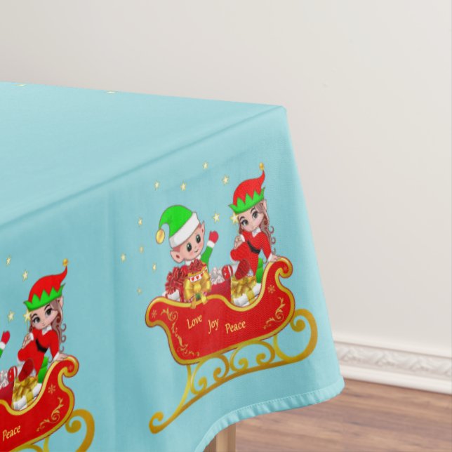 Niedliche Weihnachtselfen auf Schlitten auf hellbl Tischdecke (Beispiel)